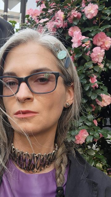 Katherine is wearing solid sterling silver stud earrings and a choker necklace by Xover0 at a Tokyo bus stop surrounded by camellia trees.