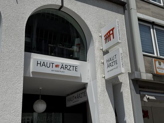 Arkaden mit Leuchtreklame: „Haut Ärzte am Marktplatz“