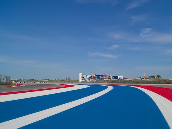 The painted should of the racetrack in red white and blue with the redbull sign in the background
