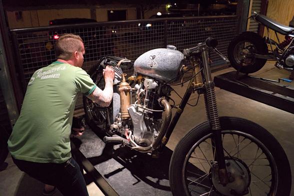 A man signing a custom built motorcycle that is covered in other peoples signatures