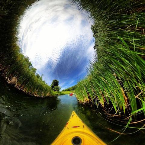 One of a series of photographs in which two people are pictured hiking, biking, and kayaking throughout a beautiful and verdant state park in central Minnesota under cloudy blue late-summer skies.