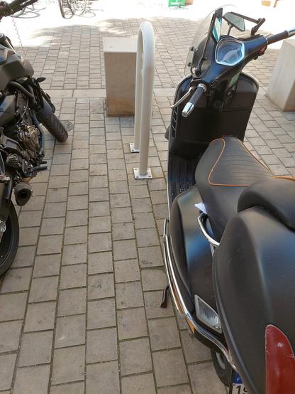 un scooter garé sur une place vélo, avec une notice verbalisation sous le siège