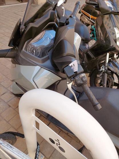 scooter à côté d'un arceau vélo, avec une verbalisation attaché au guidon