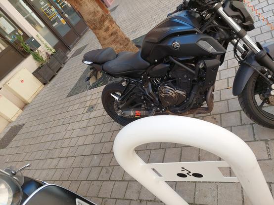 moto garé à côté d'un arceau, avec notice de verbalisation sous le siège.