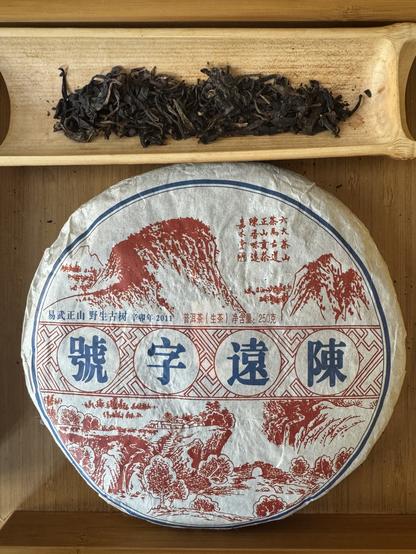 Puerh tea cake in wrapper next to dry tea leaves