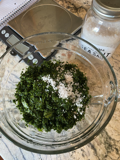 It’s a top view of a clear batter bowl with dark green cilantro and white salt.  The scale and the jar of salt are at the top.