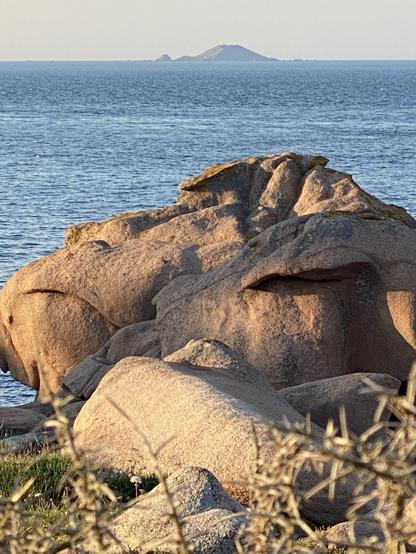 Rocks on the Pink granite coast between Perros Guirec and Ploumanac’h during the Golden Hour. In the background the Rouzic Island of the Sept Îles