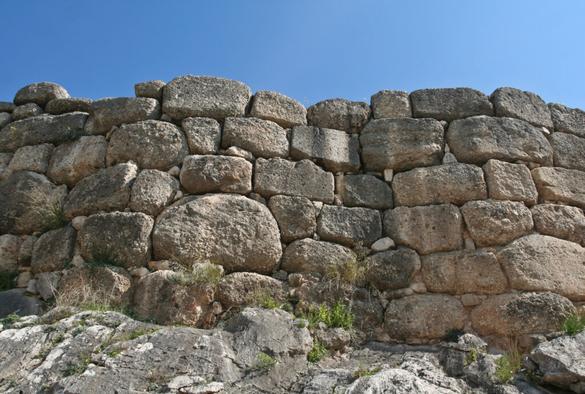 A wall of gigantic rounded stones roughly shaped and placed together with a few smaller stones to fill gaps
