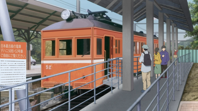 An orange single coach train with some people standing on the platform