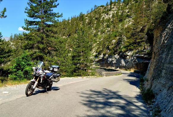 a curvy road around a mountain and a parked motorbike