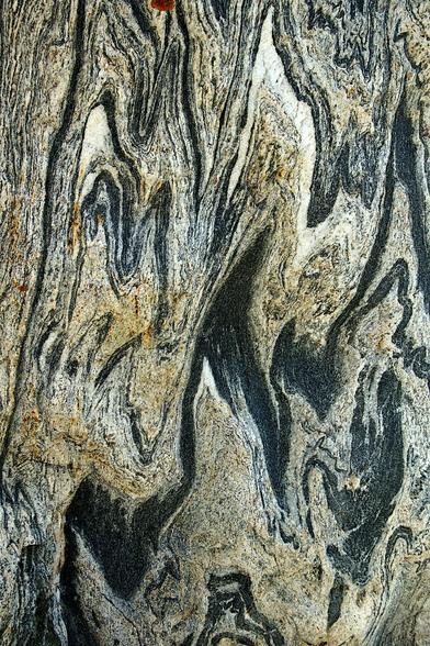 A black, gray and white pattern of a water polished granite boulder.