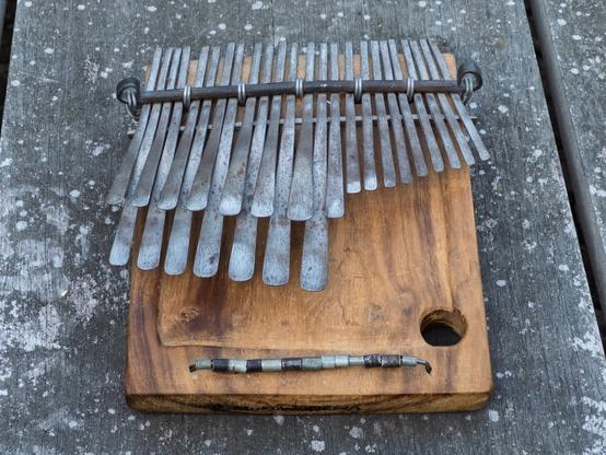 A rustic mbira with metal tines rests on a wooden surface.