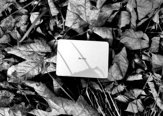 A black-and-white photo of an Oblique Strategy card. The card reads: 'Be dirty'.