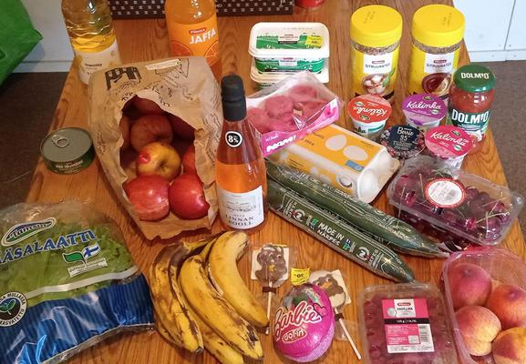 photo of a kitchen table full of groceries, most of it fresh produce (apples, peaches, cherries, raspberries, bananas, cucumbers and salad) plus reduced easter candy, a bottle of wine, eggs, cooking oil etc.