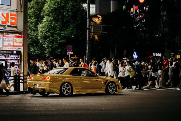 photo of a yellow tuner car at night at a crossing in Tokyo