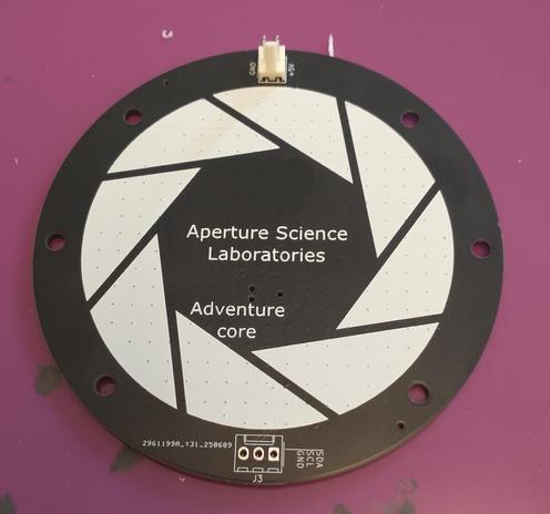Back of the previous circuit board, which is entirely clear of components apart from a single power connector. The artwork has "Aperture Science Laboratories" and "Adventure core" written on, and has the Portal game logo.