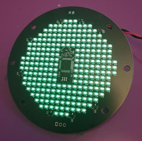 The front of the same circuit board with the green LEDs shining