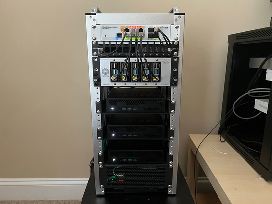 The front of the minirack build in the T2.  From top to bottom: CRS112 Mikrotik switch, a shelf of 5 RPis (4Bs), 3 Minisforum MS-A2s, and the bottom holds the PiKVM + Switch.