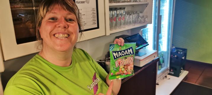 Sandra hält eine Packung Fruchtgummis hoch, die "Pinballs" heißen.