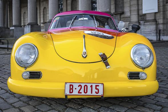 Front view of yellow beetle oldtimer reminding of a face with big round eyes and a big smile. An interesting reflection of the Brussels' Cinquantenaire Arch  is also visible on the hood.