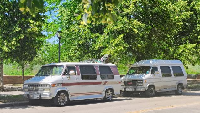 My 1993 Chevy G20 parked in front of a GMV Ventura with greenery behind.