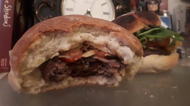 Two of the hamburgers lay on the board to feast on in the living room. The filling can be seen inside of the half eaten burger