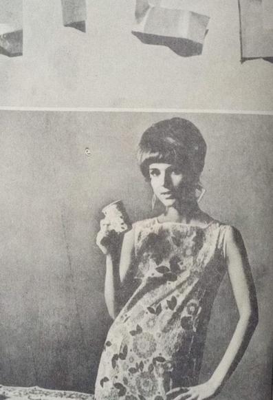 Una antigua revista mostrando la tendencia de vestidos de papel en Nueva York, con un título destacado y una imagen de una mujer usando un vestido de papel, sosteniendo un vaso.