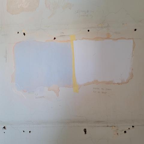 An old lime plaster wall with a paint stripped space with new areas of distemper and mineral silicate paints.