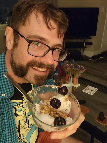 Me (a bearded grinning white guy) holding up a small bowl of ice-cream. There's 3 cherries in it and some granola. It's not a very artful presentation but I look pleased anyway.
