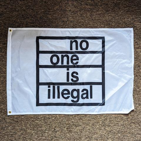 biały transparent z czarnym logiem akcji NO ONE IS ILLEGAL