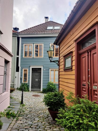 Photography of brightly colored small wooden houses in narrow cobbled alleys.