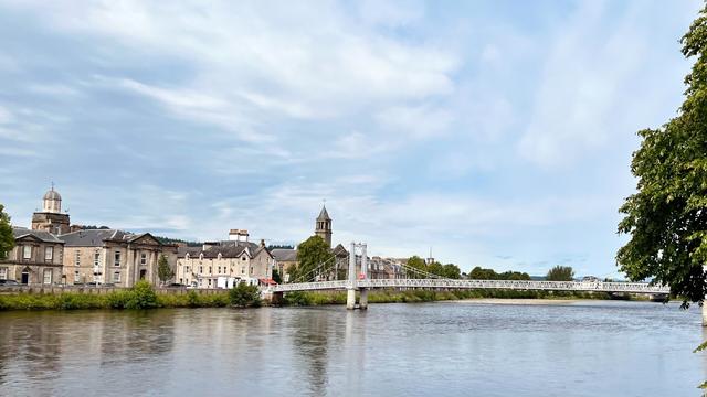 View over the River Ness, in the distance a white suspension bridge, and buildings on the opposite shore