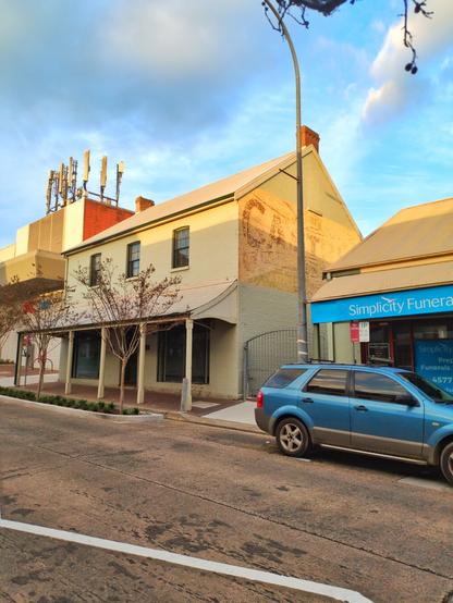 A two-storey colonial-style cottage with a verandah in front of its ground-floor shop.