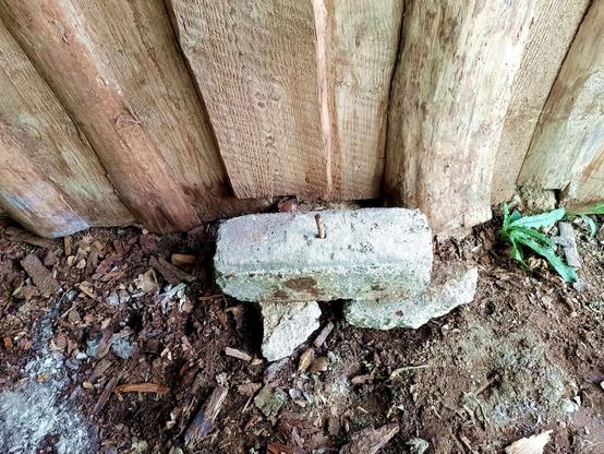 A piece of concrete sitting on two other pieces. A steel bar is hammered through a hole in the center and deep into the ground. It sticks out the top to impale a log on.