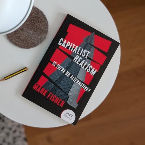 A photo of the book "capitalist realism" by Mark Fisher lying on a bedside table.