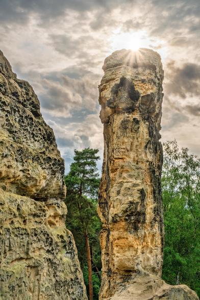 Eine Klippe Formation und über dem in die Höhe ragenden Felsen bricht sich die Sonne und erzeugt einen Sonnenstern.