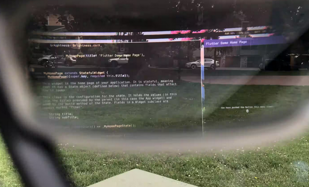 Photo through the lenses of AR glasses showing a text editor with some code