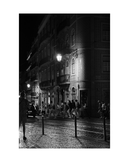 dimly lit lisbon neighborhood by night, a lot of young people crossing the street, shot in black and white