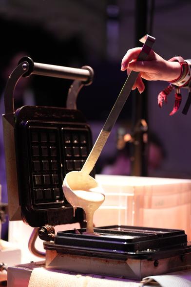 Waffelteig wird mit einer Kelle ins Waffeleisen gegeben