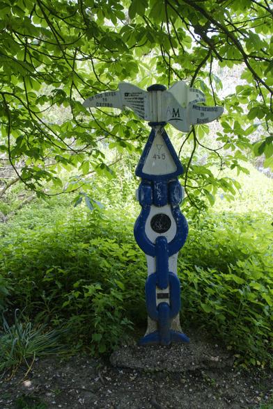 A blue chained post, with white infills. There are odd shaped pointers in white pointing in all directions. The text is in black but not readable.