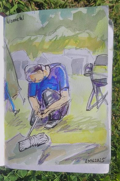 Aquarellskizze im kleinen Skizzenbuch: Person im blauen T-Shirt kniet auf dem Rasen eines Zeltplates vor einer oliv-farbenen Plane und hantiert mit einer Rolle weißen Seils. Dahinter Zelte, daneben ein Campingstuhl