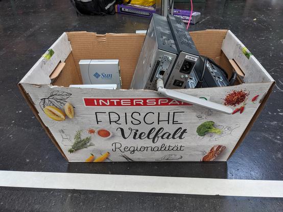 A paper box full of old Sun Microsystems computer hardware. The box is branded by a supermarket, saying "fresh varieties" (originally in German: Frische Vielfalt).
