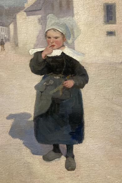 Détail d'un tableau : au centre, une petite fille, habillée avec un vêtement breton (robe noire, coiffe blanche, grand col blanc), met un doigt sur sa bouche ; elle est légèrement tournée vers la gauche et se tient debout au centre d'une grande rue ensoleillée. Son ombre portée, forte, est peinte à gauche, bleue. Le fond du tableau est en majorité blanc cassé ; à l'arrière, des maisons et on devine quelques personnages tout au fond à gauche.
Il s'agit d'un tableau de Robert Murdoch Wright, intitulé Fillette bretonne à Pont-Aven, daté de 1891