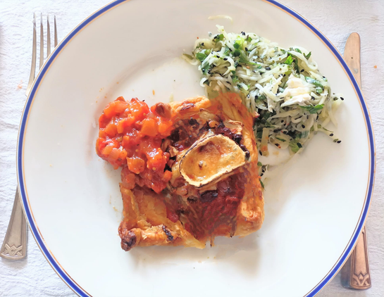 ein viereckiges Rück Quiche mit dem Belag wie beschrieben, daneben ein Klecks von dem Chutney und eine Portion hellgrüner Julienne-Salat