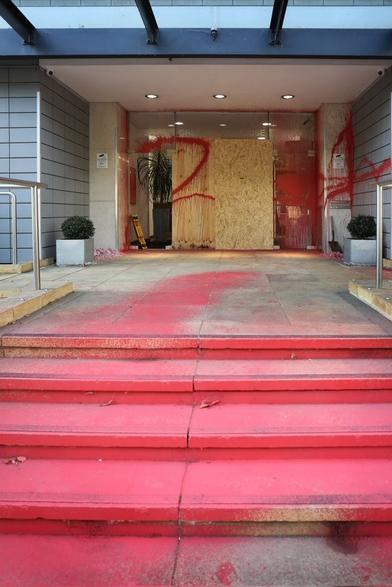 Picture of an office building in Chelmsford.  The steps leading to the entrance have been painted red, glass in the door has been smashed (and replaced with chipboard) and paint has been sprayed on other parts of the building.