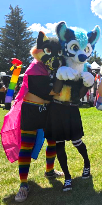 Two fursuiters pose for a photo at a pride festival.