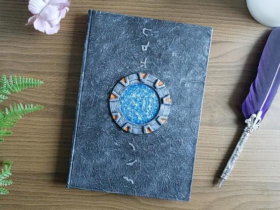 A5 Notebook in silver tone, with a Stargate in the middle and coordinates to Earth on top and bottom.