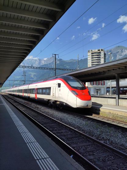 Foto. Ein weisser Zug im Bahnhof.
