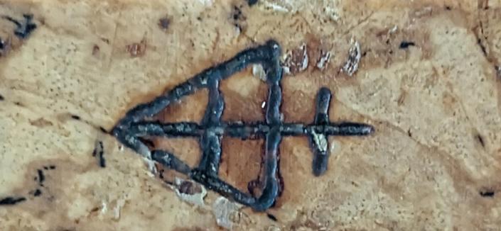 A closeup photo of a symbol that consists of a triangle with a plus sign inside of it and another plus sign on the outside.