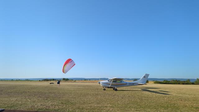 Cessna 182 früh morgens und eine Gleitschirmfliegerin beim Groundhandling auf der Piste.